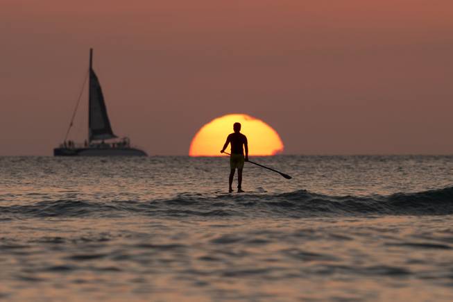 A paddle boarder looks out over the Pacific Ocean as the sun sets off Waikiki Beach, in Honolulu, on Tuesday, Dec. 31, 2013. 