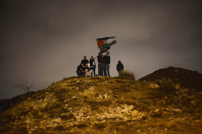 Palestinians wave their national flag as they await the release of Palestinian prisoners in Jerusalem, Tuesday, Dec. 31, 2013. Israel released more than two dozen Palestinian prisoners convicted in deadly attacks against Israelis early Tuesday as part of a U.S.-brokered package to restart Mideast peace talks.