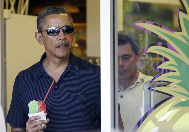 President Barack Obama holds his shave ice as he exits Island Snow to greet people waiting outside, Tuesday, Dec. 31, 2013, while vacationing in Hawaii.