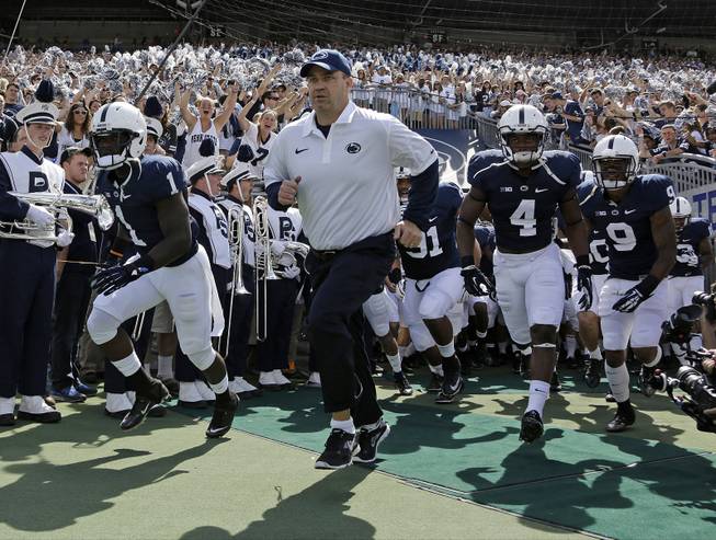 Penn State coach Bill O'Brien leads his team onto the field at Beaver Stadium for an NCAA college football game against Eastern Michigan in State College, Pa., Sept. 7, 2013.