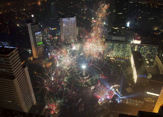 Fireworks explode as thousands of people line the streets of downtown Jakarta to welcome in the New Year in Indonesia, Wednesday, Jan. 1, 2014.