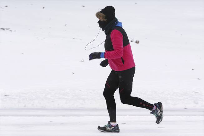 A woman runs on a snow-covered street after an overnight snow storm moved through the Midwest heading for the upper Northeast, Thursday, Jan. 2, 2014, in Springfield, Ill.