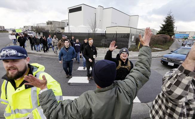 A small group of machinists union members are greeted by a supporter as they march away from a Boeing factory building toward the machinists' union hall in Everett, Wash., Dec. 18, 2013.