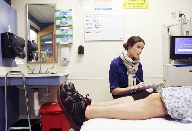 Hannah Lobingier, who works for a program that tries to keep Medicaid patients from relying on emergency rooms, with a patient in the ER at Providence St. Vincent Medical Center in Portland, Ore., April 3, 2013.