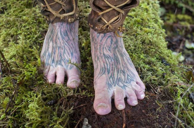 Mick Dodge's feet are tattooed with the images of roots. He stands on some moss at his cabin along the Sol Duc River near Forks, Wash., on January 3, 2014. Dodge is the subject of "The Legend of Mick Dodge" on the National Geographic Channel.