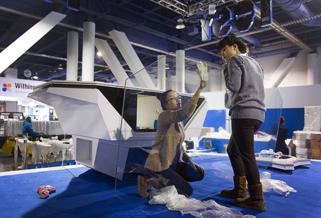Ly Nguyen of Vietnam cleans a glass desktop at the Tosy Robotics Joint Stock Company booth during set up for the 2014 Consumer Electronics Show (CES) at the Las Vegas Convention Center Saturday, Jan. 4, 2014.