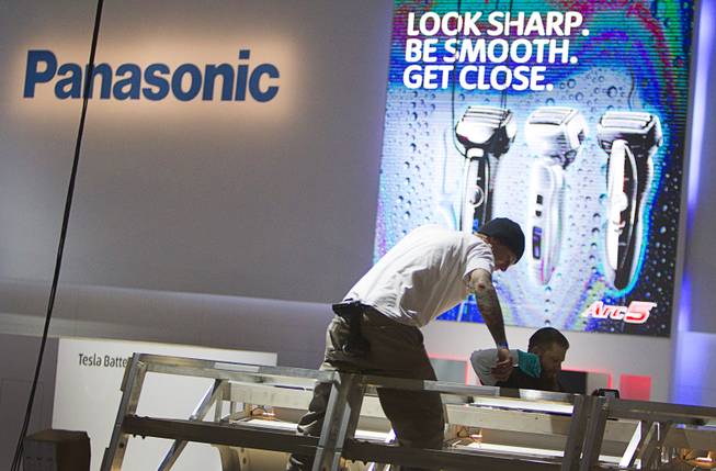 Workers build a display at the Panasonic booth in preparation for the 2014 Consumer Electronics Show (CES) at the Las Vegas Convention Center Saturday, Jan. 4, 2014.
