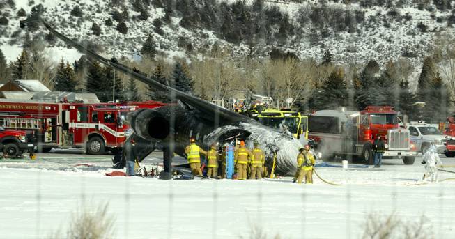 Emergency crews work near a passenger plane that crashed upon landing at the Aspen-Pitkin County Airport in Aspen, Colo., Sunday, Jan. 5, 2014.