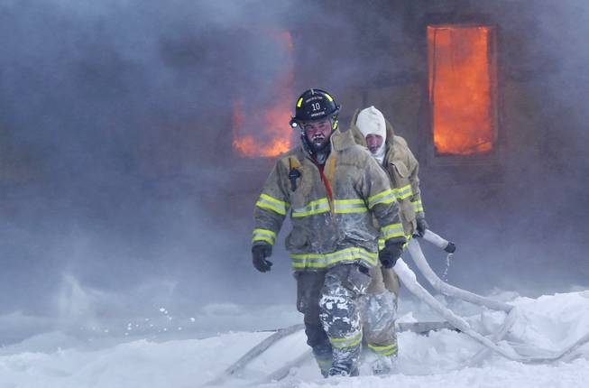 Firefighters contend with dangerously cold temperatures and wind as they battle a structure fire in an industrial park Monday, Jan.6, 2014, just south of Brookston, Ind. 