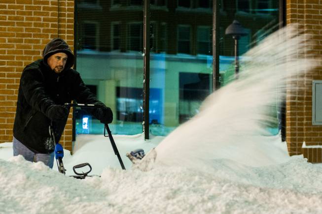 Genesee resident Tony Felice, 42, grimaces as he approaches the one-hour mark of snowplowing in a 100-foot area outside of the WadeTrim Building where a recorded 16.2 inches of snow fell, Monday, Jan. 6, 2014, in downtown Flint, Mich. "It's not fun," he said. Michigan residents braced Monday for temperatures to dive further to dangerously cold levels as they dug out following a multi-day storm that shuttered schools and government offices across the state.