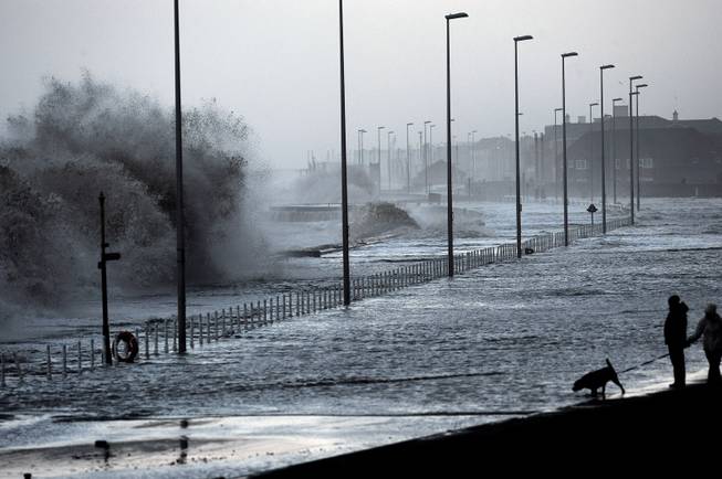 Water covers the coastal roads at Clevelys near Blackpool, England as large waves crash over the sea defenses as high tides and huge waves hit the west coast of the UK, Monday, Jan. 6, 2014. 