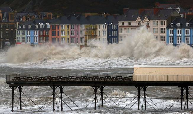 Waves crash against the promenade in Aberystwyth, Wales  Monday Jan. 6, 2014  as strong winds and high tides continue in western Britain.