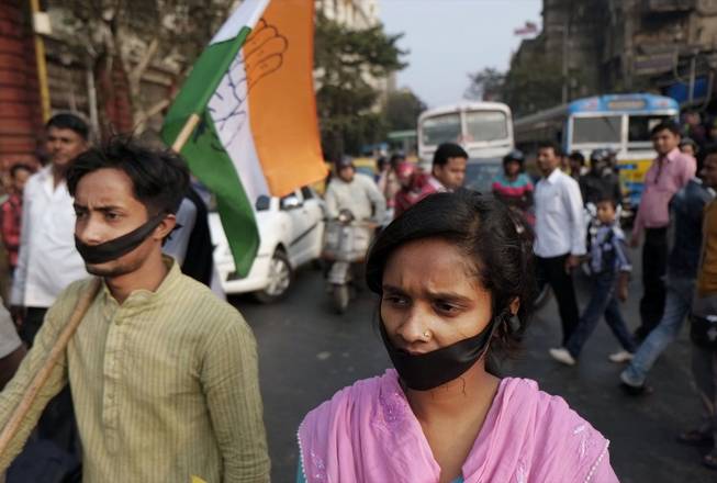Activists of Indian National Congress with black bands around their mouths block traffic during a protest against a gang rape and murder of a 16-year-old girl at Madhyamgram, about 16 miles north of Kolkata in West Bengal, India, Jan. 3, 2014. 