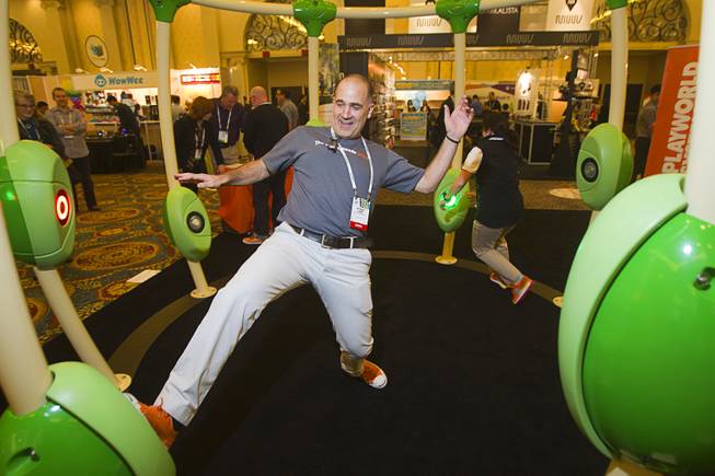 Michael Laris (L) and Tracey Cassidy play the Neos 360  "Light Grabber" game by Playworld Systems during the 2014 International Consumer Electronics Show (CES) in Las Vegas, Jan. 8, 2014. The system is designed for schools, parks and public areas, Cassidy said.