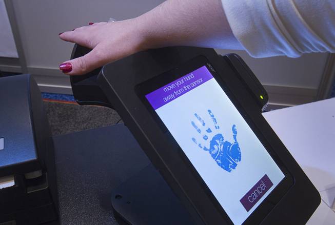 A woman registers her palm on a PulseWallet, a point-of-purchase device, during the 2014 International Consumer Electronics Show (CES) in Las Vegas, Jan. 8, 2014. The system measures vein patterns in the palm. After confirming a person's identity, the purchase can be paid with a "digital wallet" linked to a credit card, debit card, a bank account or even paid in bit coins.
