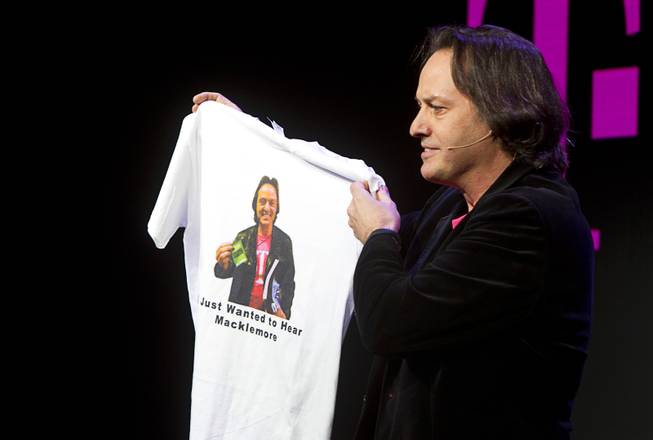 T-Mobile CEO John Legere  holds a custom-made T-shirt with his image during a news conference at the 2014 International Consumer Electronics Show (CES) in Las Vegas, Jan. 8, 2014. The shirt is a reference to Legere getting kicked out of a AT&T-sponsored party featuring a performance by Macklemore.