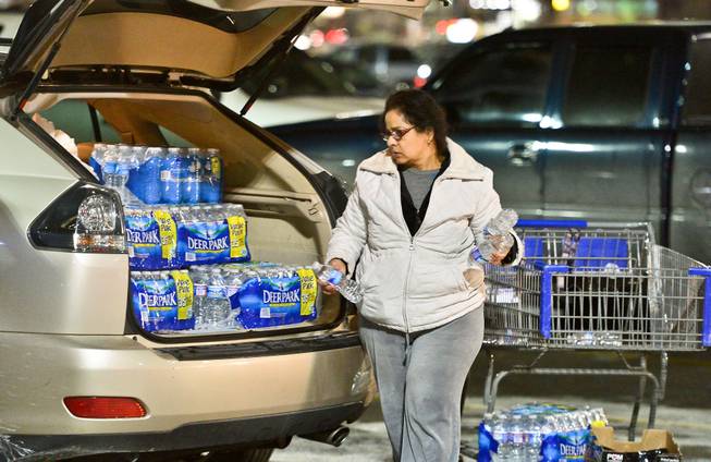 Charleston resident Niru Parikshak loads up the back of her car with bottled water Thursday Jan. 9, 2014, in Charleston, W.Va. Sam's Club and every retailer for a 20-mile radius sold out of bottled water after a chemical leak Thursday morning up river from the WV American Plant on the Elk River forced the water plant to shut down.