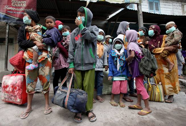 Villagers wait for the bus as they flee their homes following the eruption of Mount Sinabung in Payung, North Sumatra, Indonesia, Wednesday, Jan. 8, 2014.