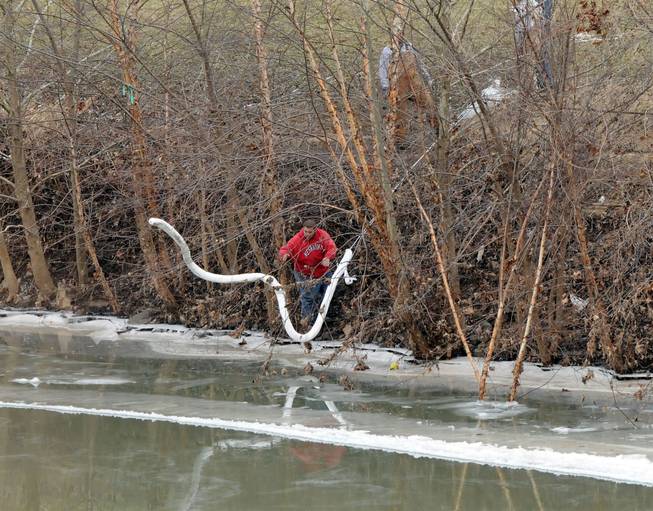 A Freedom Industries worker places a boom in the Elk River Thursday, Jan. 9, 2014, at the site of a chemical leak in Charleston that has fouled the drinking water in five West Virginia counties.