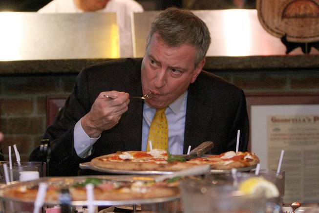 New York Mayor Bill de Blasio eats pizza with a fork at Goodfellas Pizza in the Staten Island borough of New York, Friday, Jan. 10, 2014. That's a no-no for most New Yorkers.