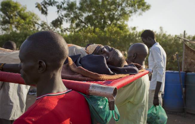 An elderly man who was injured in the recent violence is carried through the camp for displaced people where he sought shelter in order to be brought back to the main hospital for treatment, from which he had previously left because he didn't feel safe there, in the capital Juba, South Sudan Saturday, Jan. 11, 2014.