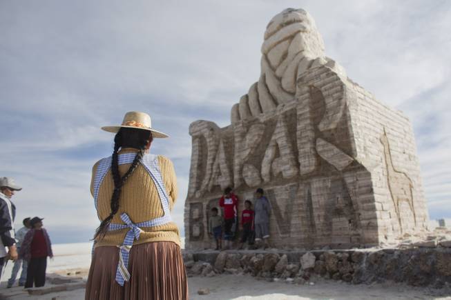 An Aymara Indigenous woman looks at a monument made of salt to welcome the Dakar Rally at the Uyuni Salt Flats in Uyuni, Bolivia,  Saturday, Jan. 11, 2014. Dakar rally Motorcycles and quads will race through parts of the Uyuni Salt Flats on Jan. 13, 2014. 