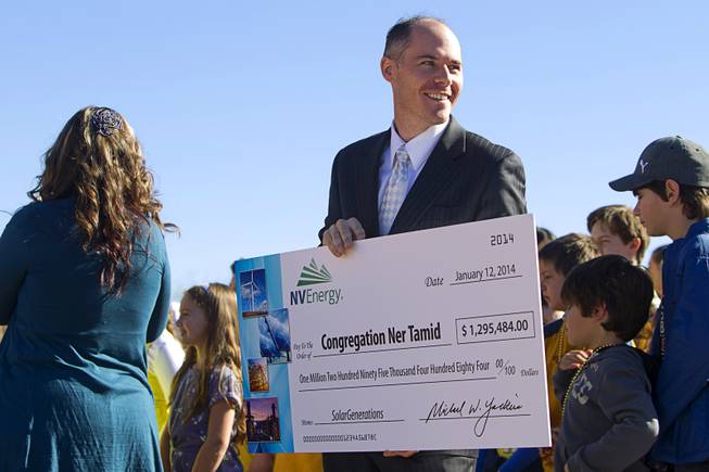 Ben Robertson, coordinator for NV Energy's renewable generations program, holds a ceremonial rebate check during a news conference to "unveil" a solar photovoltaic field at Congregation Ner Tamid in Henderson Sunday, Jan. 12, 2014. The $1.6 million project, a partnership of Congregation Ner Tamid, NV Energy and Hamilton Solar, will produce about 75 percent of the temple's power usage on average, said Matthew Weinberger, Hamilton Solar's director of business development.