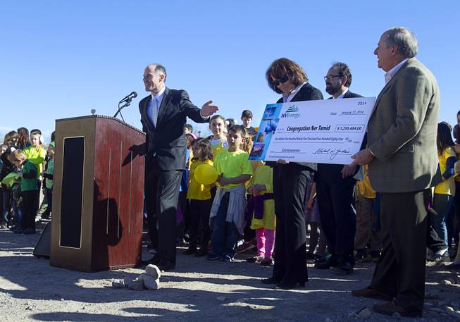 Ben Robertson, left, coordinator for NV Energy's renewable generations program, presents a ceremonial rebate check to members of Congregation Ner Tamid during a news conference to "unveil" a solar photovoltaic field at the temple in Henderson Sunday, Jan. 12, 2014. The $1.6 million project, a partnership of Congregation Ner Tamid, NV Energy and Hamilton Solar, will produce about 75 percent of the temple's power usage on average, said Matthew Weinberger, Hamilton Solar's director of business development.