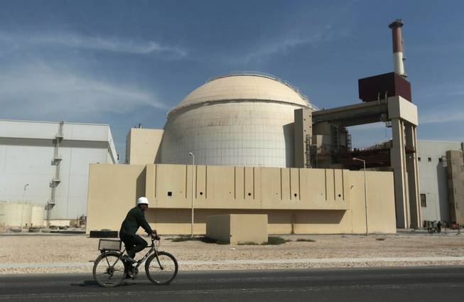 In this Oct. 26, 2010, file photo, a worker rides a bicycle in front of the reactor building of the Bushehr nuclear power plant, just outside the southern city of Bushehr. Iran and six world powers have agreed on how to implement a nuclear deal struck in November, with its terms starting from Jan. 20, officials announced Sunday. 