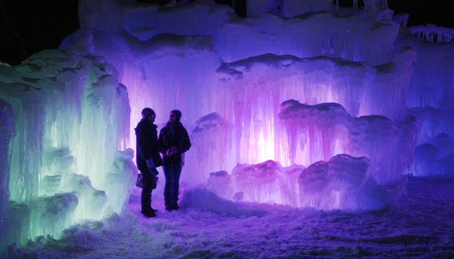 In this photo taken Wednesday Jan. 8, 2014 patrons tour an ice castle at the base of the Loon Mountain ski resort in Lincoln, N.H. The ice castle begins to grow in the fall when the weather gets below freezing and thousands of icicles are made and harvested then placed around sprinkler heads and sprayed with water.  