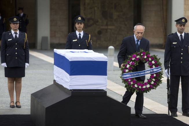 Israel's President Shimon Peres lays a wreath next to the coffin of late Israeli Prime Minister Ariel Sharon at the Knesset plaza, Israel's Parliament, in Jerusalem, Sunday, Jan. 12, 2014. 