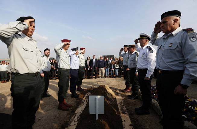 Israeli army officers salute as they stand over the grave of former Israeli Prime Minister Ariel Sharon during his funeral near Sycamore Farm, Sharon's residence in southern Israel, Monday, Jan. 13, 2014. 