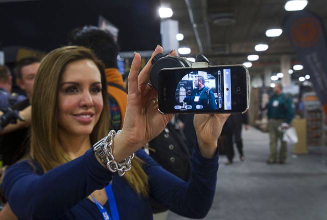 Michelle Peck holds an iPhone attached to a hunting scope at the iScope booth during the 2014 SHOT Show (Shooting, Hunting, Outdoor Trade) at the Sands Expo & Convention Center Tuesday, Jan. 14, 2014. The iScope allows hunters a full screen view of the target with both eyes open and and the option of filming the hunt through the scope. The iScope retails for $99.99.