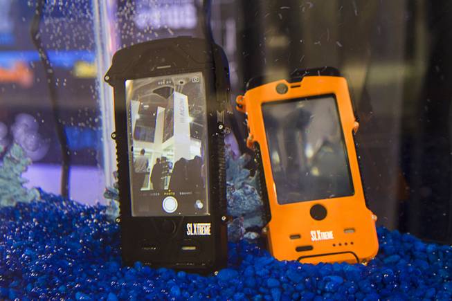 Smartphones with SL Xtreme SnowLizard cases are displayed in an aquarium during the 2014 SHOT Show (Shooting, Hunting, Outdoor Trade) at the Sands Expo & Convention Center Tuesday, Jan. 14, 2014. The cases also include an internal battery and solar charging panels on the back. The cases range in price from $129.95 to $149.99. An iPad case is expected to be available in March.