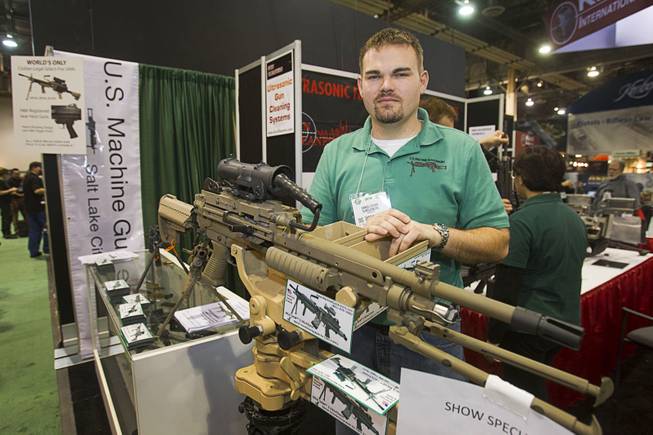 Daniel Fisher poses behind an M249 SAW full-auto machine-gun at the U.S. Machine Gun Armory booth during the 2014 SHOT Show (Shooting, Hunting, Outdoor Trade) at the Sands Expo & Convention Center Tuesday, Jan. 14, 2014. The American-made weapon is available to civilians in a semi-auto version, he said.