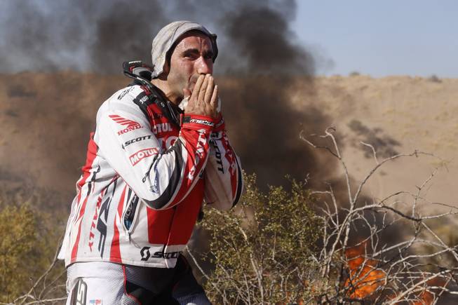 Honda rider Paulo Goncalves, of Portugal, cries as he watches his motorcycle burn during the fifth stage of the Dakar Rally between the cities of Chilecito and San Miguel de Tucuman, Argentina, Thursday, Jan. 9, 2014. 