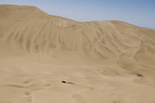 Mini driver Stephane Peterhansel and co-pilot Jean Paul Cottret, both of France, race through the dunes during the ninth stage of the Dakar Rally between the cities of Calama and Iquique, Chile, Tuesday, Jan. 14, 2014