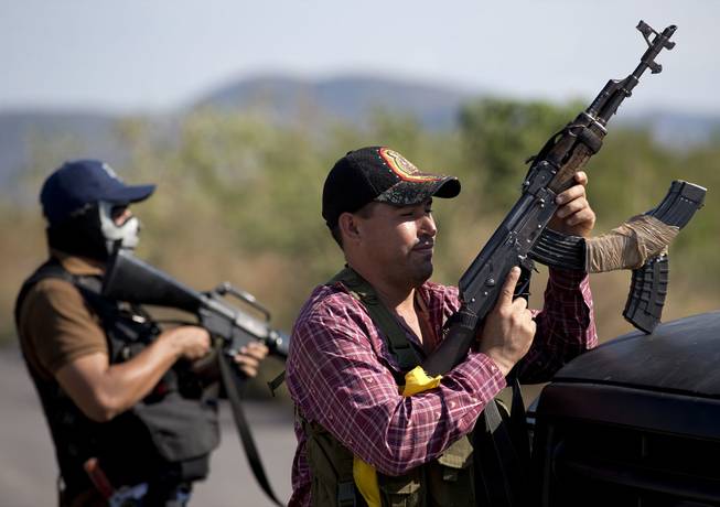 Armed men belonging to the Self-Defense Council of Michoacan stand guard at a checkpoint at the entrance of Antunez, Mexico, Tuesday, Jan. 14, 2014. 