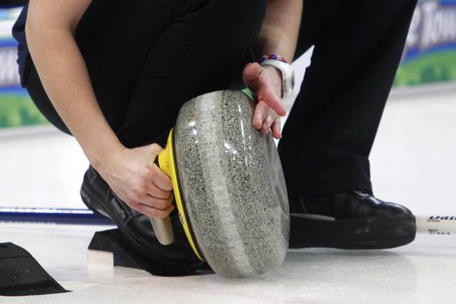 A curling athlete cleans the bottom of a stone before throwing it during the first day of the 2014 World Financial Group Continental Cup of Curling at the Orleans Arena Thursday, Jan. 16, 2014. Of the twelve teams competing from around the world, nine of them will represent their respective country at the upcoming Olympics in Sochi, Russia.