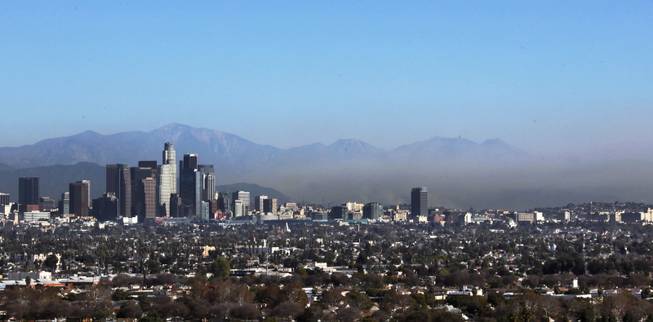 Smoke from the Colby fire spreads over the Los Angeles skyline, with downtown seen at left, Thursday, Jan. 16, 2014. Homes burned in a wildfire threatening neighborhoods in dangerously dry foothills of Southern California's San Gabriel Mountains on Thursday, fanned by gusty Santa Ana winds that spit embers into the city below. 