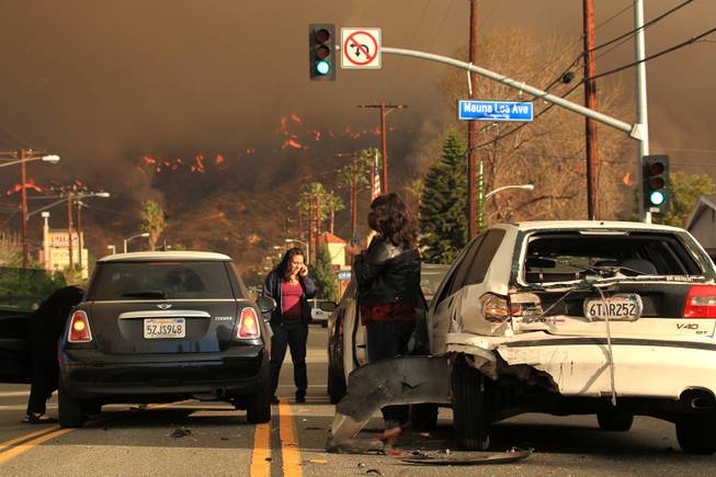 Motorists exchange information after a car accident as a wildfire burns in the hills just north of the San Gabriel Valley community of Glendora, Calif. on Thursday, Jan 16, 2014. 