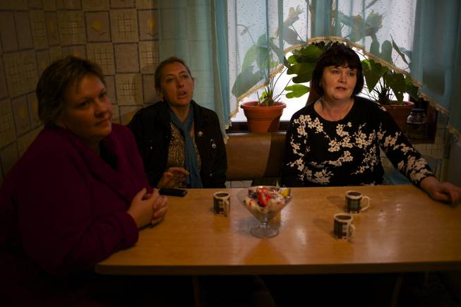 In this picture taken on Wednesday, Nov. 27, 2013, Alexandra Krivchenko, left, Nadezhda Kurovskaya, center, Irina Kharchenko, right, residents of 5a Akatsiy, street drink tea in the village of Vesyoloye outside Sochi, Russia.