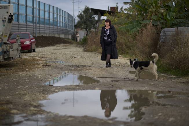 In this photo taken Wednesday, Nov. 27, 2013, Irina Kharchenko walks away from a screen separating the yard of her house and a federal highway in the village of Vesyoloye outside Sochi, Russia.