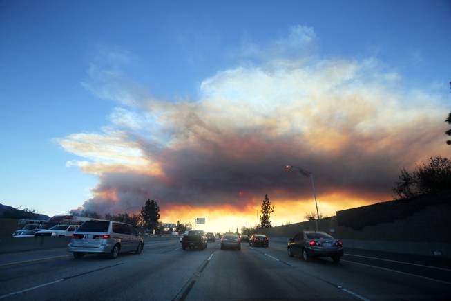 Commuters make their way along the 210 freewa as a wildfire burns in the hills just north of the San Gabriel Valley community of Glendora, Calif. on Thursday, Jan 16, 2014. 