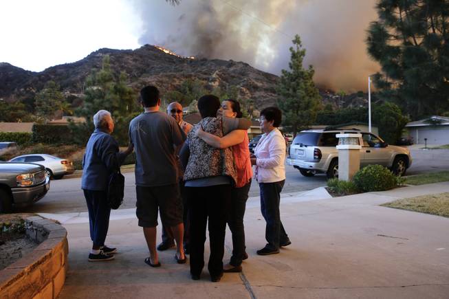 Family members comfort one another as they evacuate their home as firefighters battle a wildfire Thursday, Jan. 16, 2014, in Azusa, Calif. 