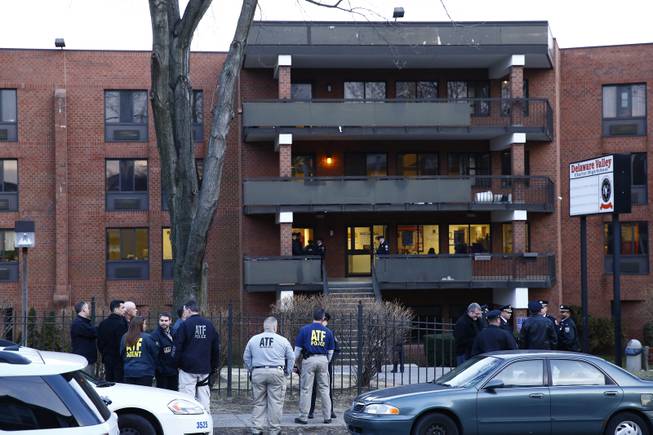 Law enforcement personnel stand outisde the Delaware Valley Charter School Friday, Jan. 17, 2014, in Philadelphia. Police say up to three boys may have been involved in the shooting of a couple of fellow students in the gym at the school.