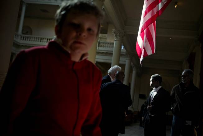 Samuel Lewis, 14, with the Atlanta Boy Choir, right, stands beneath an American Flag as fellow choir members, at left, walk up a flight of stairs at the conclusion of performing a musical selection at a ceremony paying tribute to Rev. Martin Luther King, Jr., at the Statehouse, Friday, Jan. 17, 2014, in Atlanta. 
