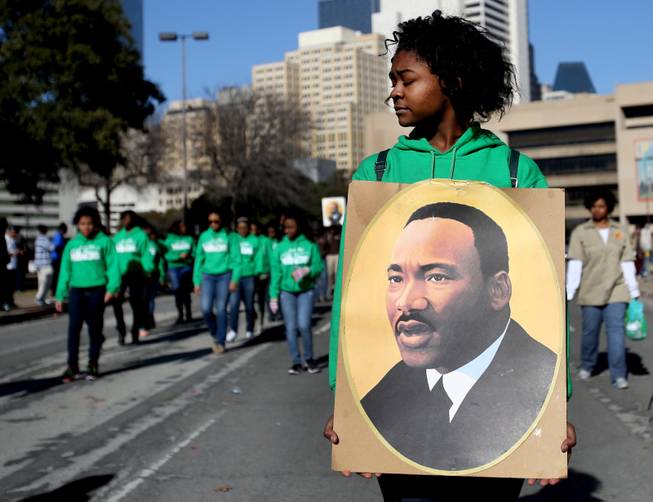 Sakidra Davis of Alpha Rho Xinos carries an image of Martin Luther King Jr. during the 32nd annual Martin Luther King Jr. Birthday Celebration's March/Parade on  Saturday Jan. 18, 2014,  in Dallas, Texas.