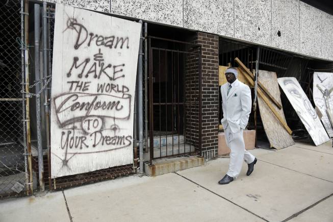 In this Thursday, Jan. 16, 2014 photo, Melvin White, founder of the Beloved Streets of America project, walks past a boarded up building during a tour of Dr. Martin Luther King Jr. Drive in St. Louis. The nonprofit is working to revitalize a downtrodden six-mile stretch of the drive named for the slain civil rights leader.