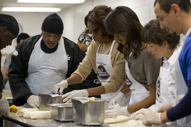 First lady Michelle Obama, center, with daughter Malia Obama and presidential adviser Valerie Jarrett, make burritos at DC Central Kitchen as part of a service project in honor of Martin Luther King, Jr. Day on Monday, Jan. 20, 2014, in Washington. Also helping were President Barack Obama and daughter Sasha Obama. 